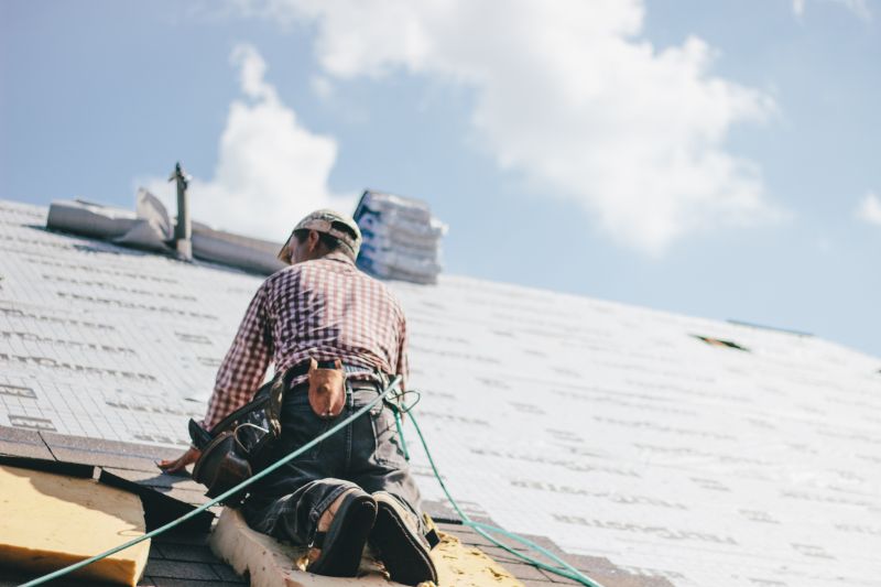 Roofer adding shingles to the roof of a building